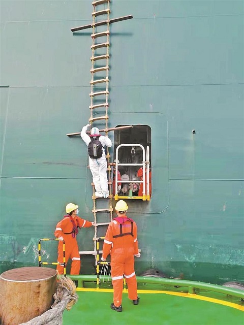 深圳港引航站引航员穿戴好防护装备、背着引航包登船.jpg